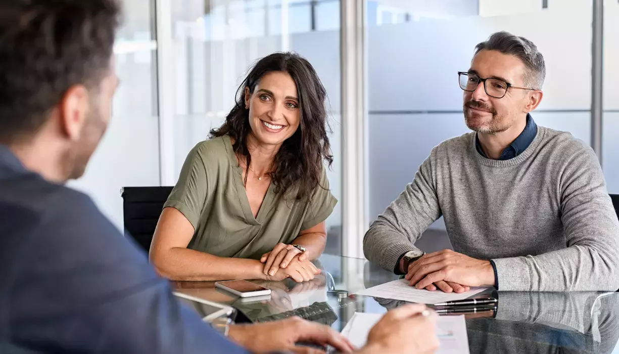 Three people sitting at the desk having a meeting.