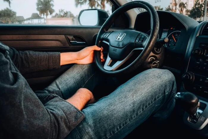 Driver sitting behind the wheel of a car, one hand resting casually on the steering wheel