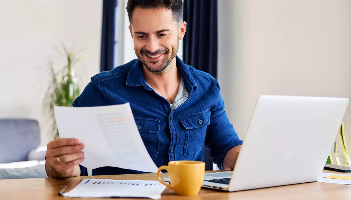 A man smiling and looking at a document.