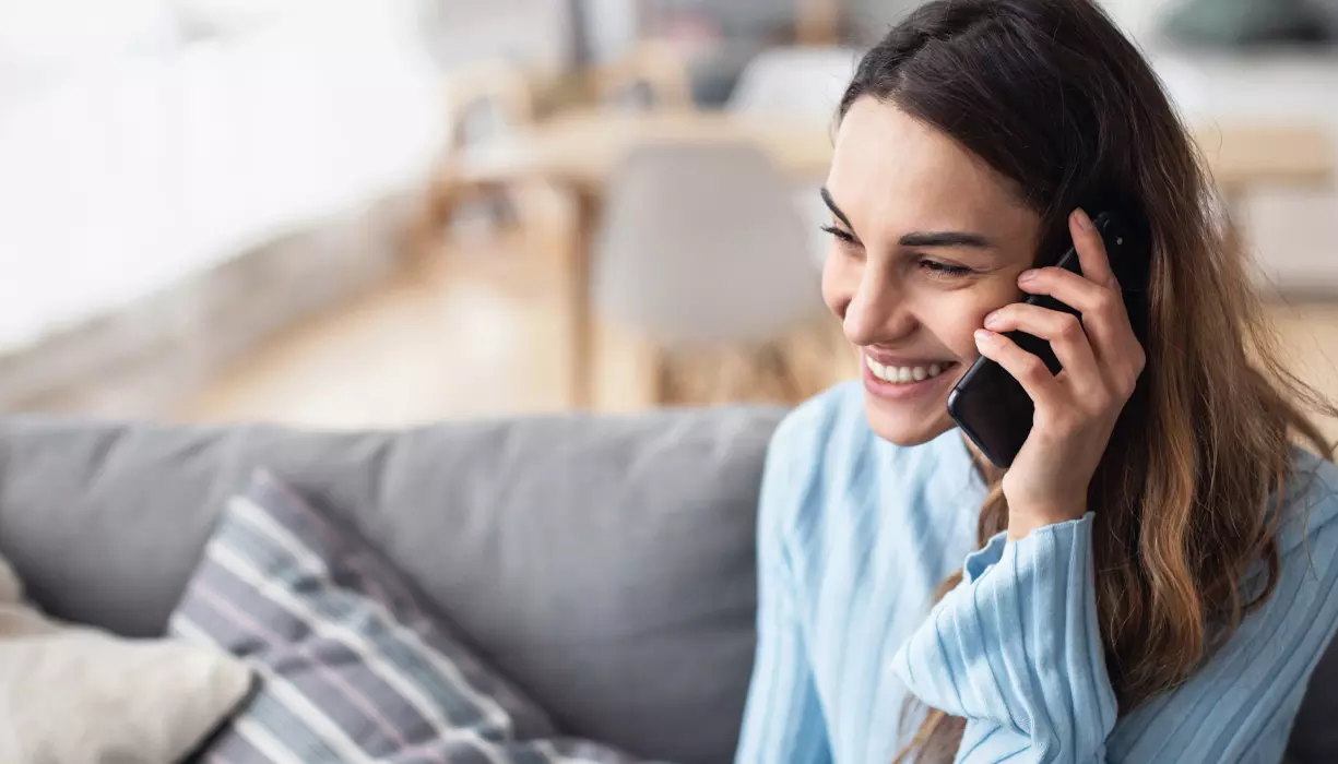 A woman smiling and talking on the phone.