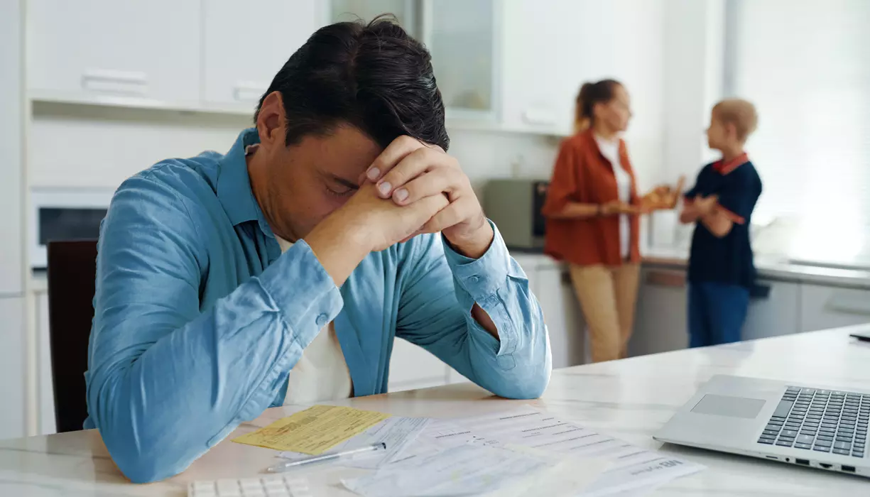 A man sitting over his bills looking concerned.