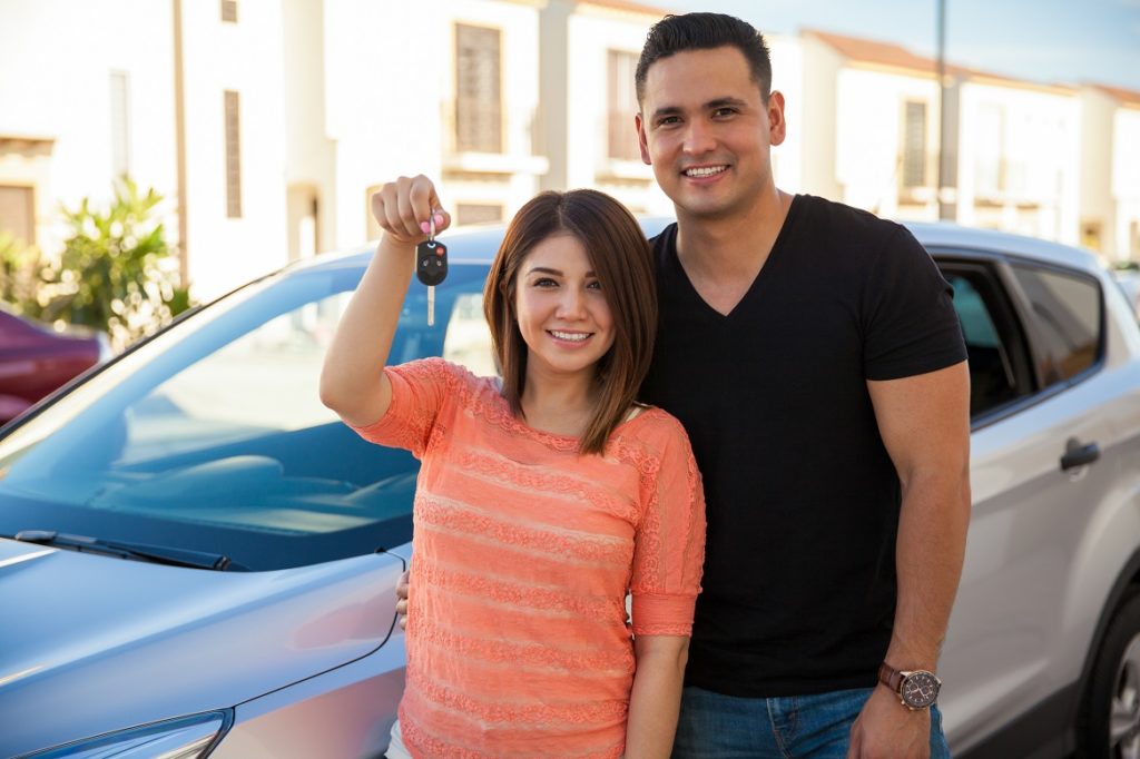 Couple with new car after buying car insurance.
